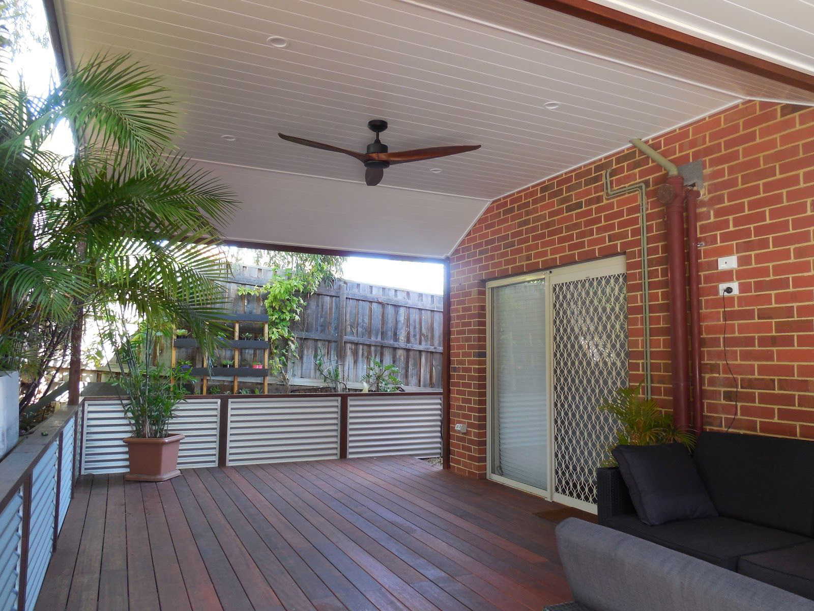 Decked & Fenced Patio With Ceiling Fan, Attached To A Brick Home.